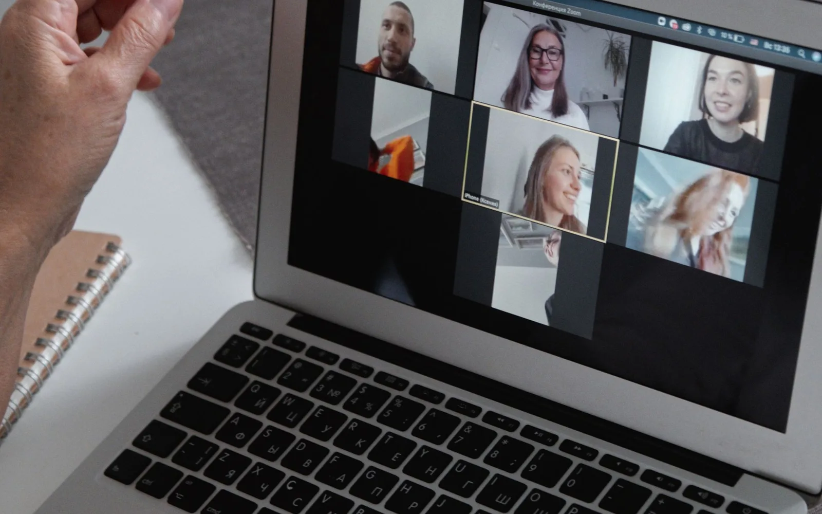 Hands at a laptop showing a group video call with several participants on screen
