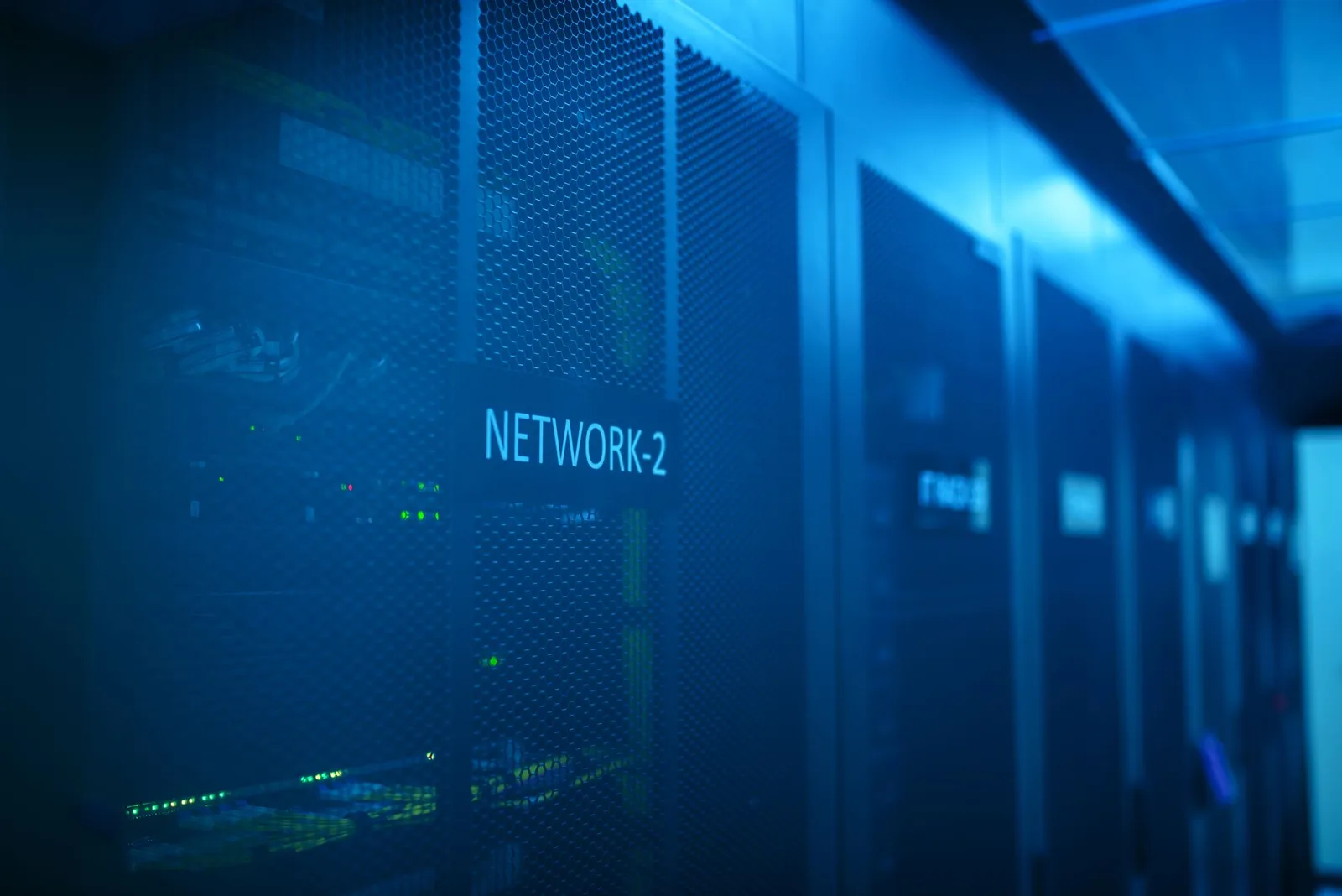 Blue-lit network server racks in a dark data center aisle, representing AI routing and decision infrastructure