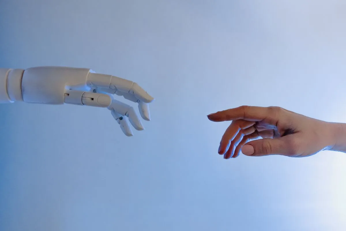 Human hand reaching toward a robotic hand — the moment control passes from your team to a rented AI agent